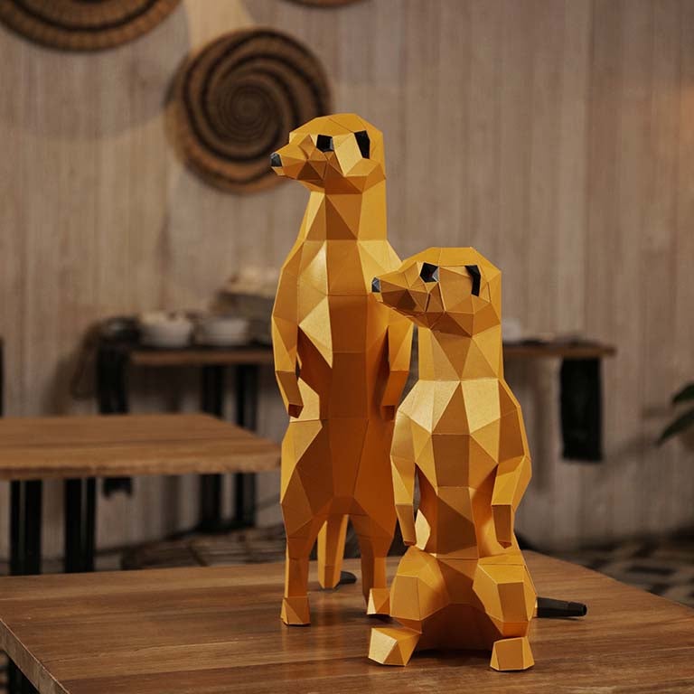 Two charming 3D paper meerkat models, one standing and one seated, showcasing intricate details and vibrant colors.