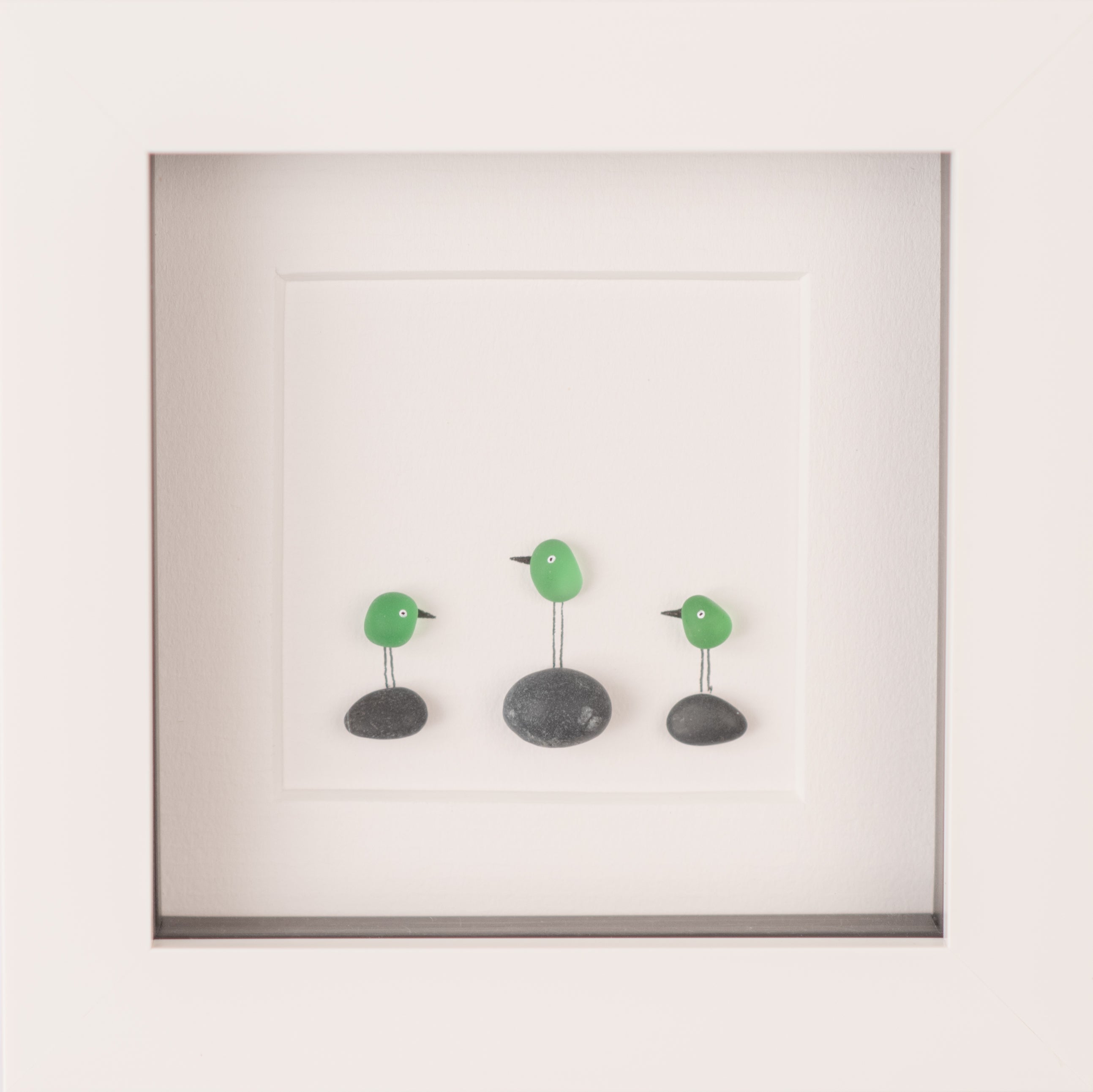 A collection of colorful Mini Sea Glass Birds displayed in elegant frames, showcasing their unique designs and natural materials.