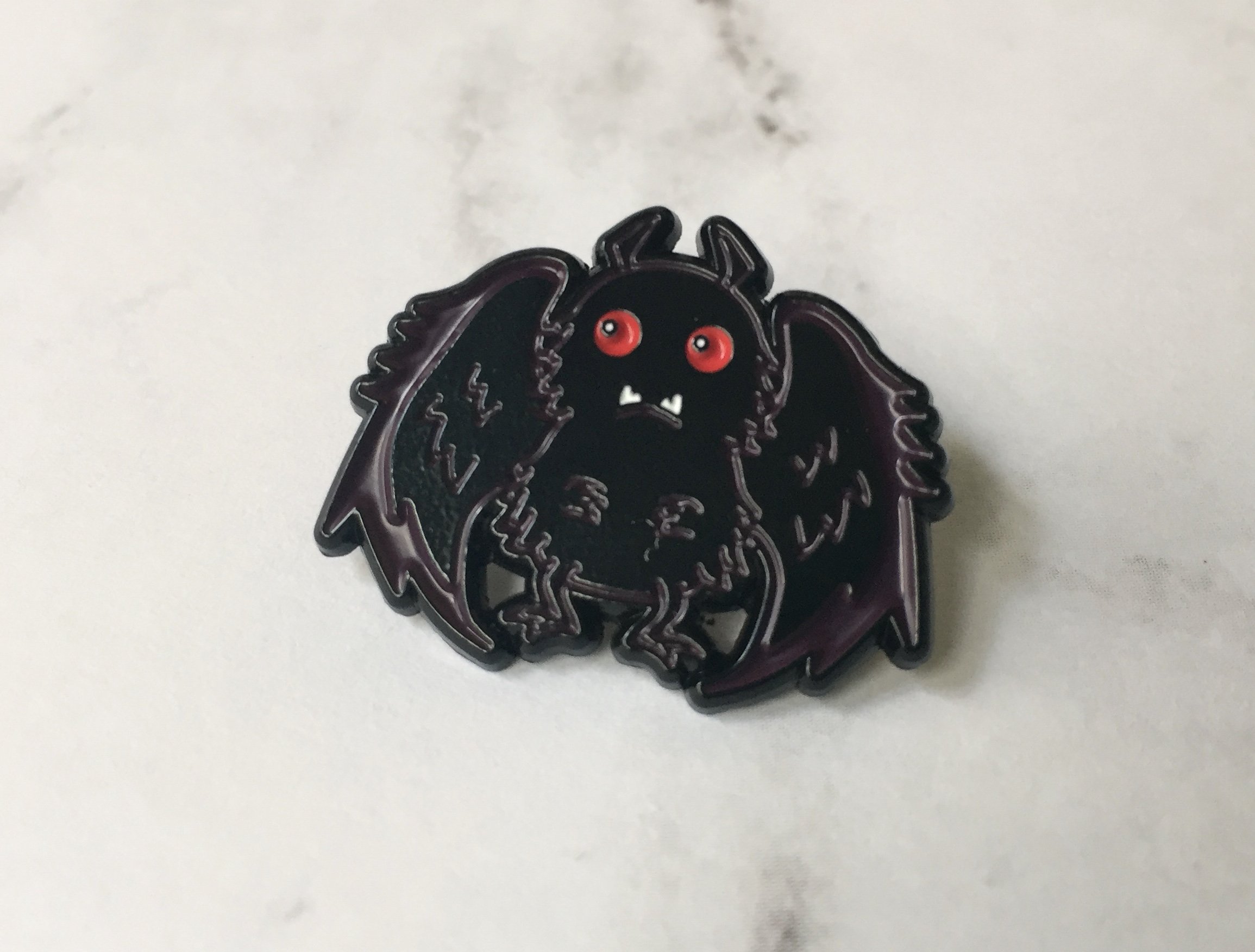 Mothman Soft Enamel Pin featuring intricate design, 1 inch in size, with a rubber pin back.