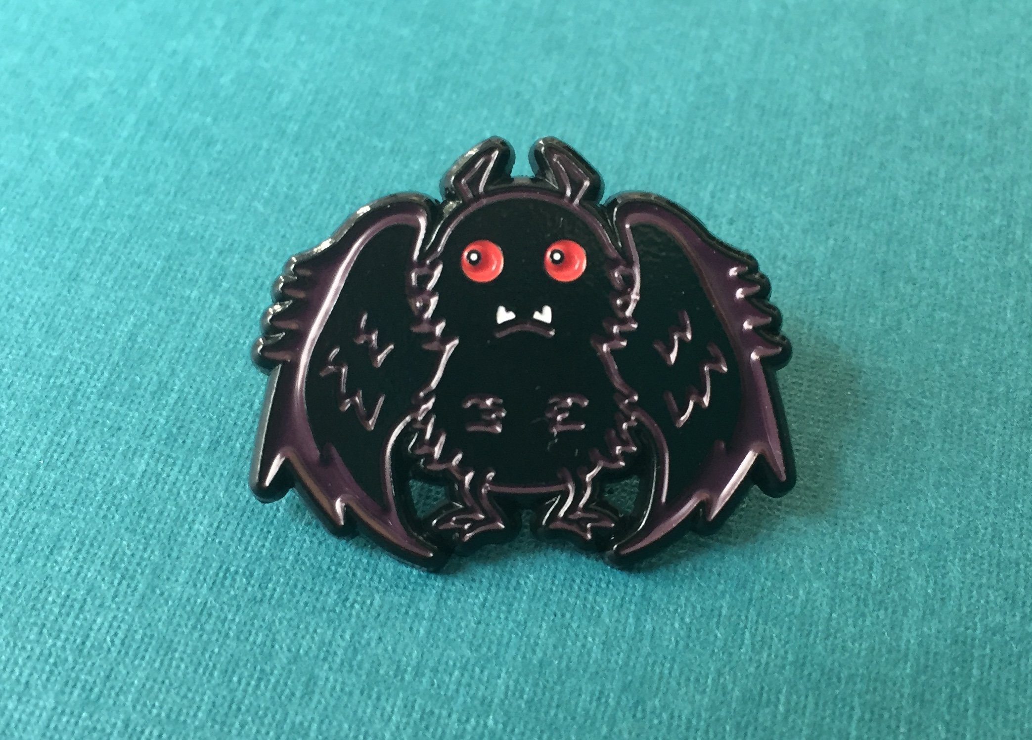 Mothman Soft Enamel Pin featuring intricate design, 1 inch in size, with a rubber pin back.