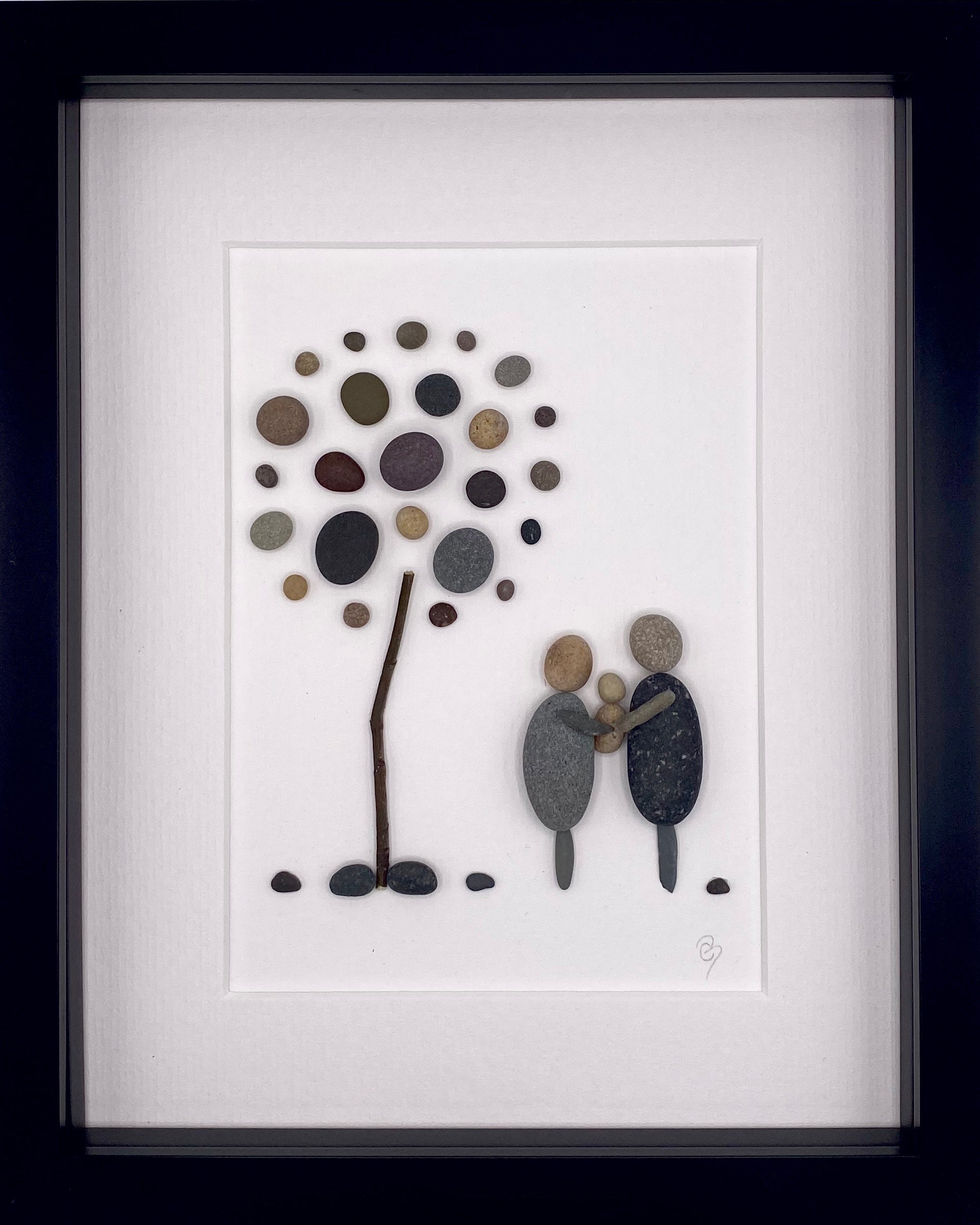 Framed artwork depicting parents holding their newborn, showcasing a nature-inspired design.