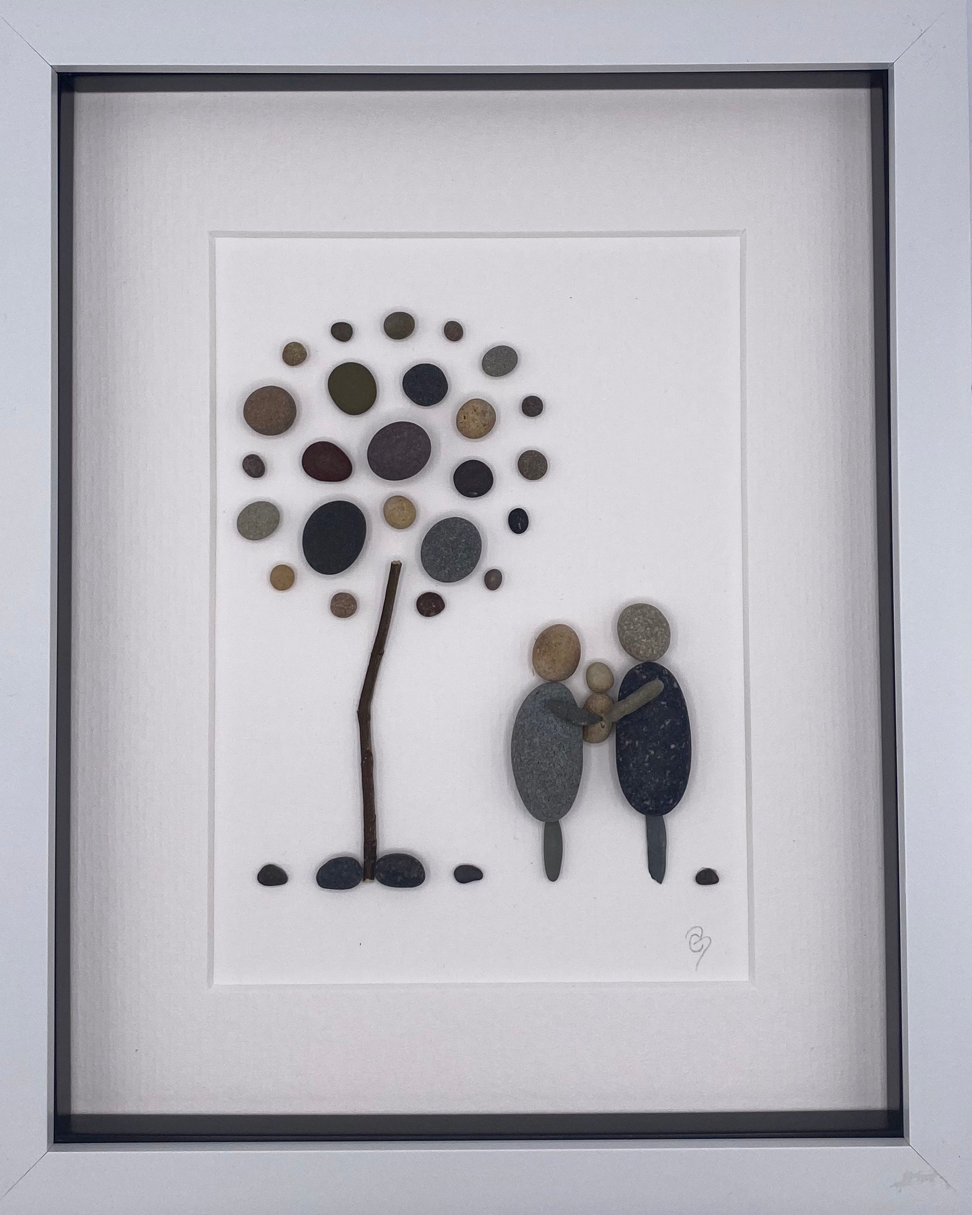 Framed artwork depicting parents holding their newborn, showcasing a nature-inspired design.