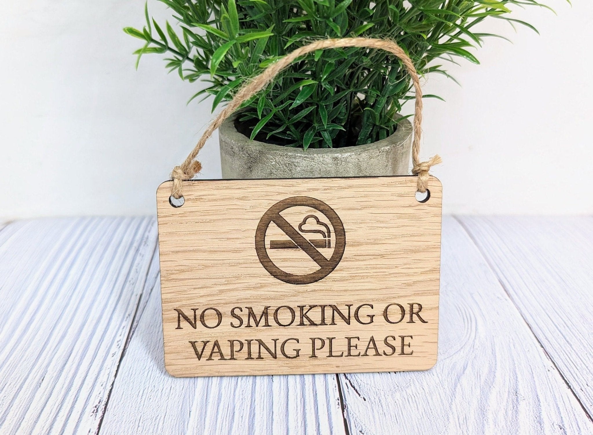 A beautifully crafted 'No Smoking or Vaping Please' wooden sign made from oak veneered MDF, showcasing its unique grain and craftsmanship.