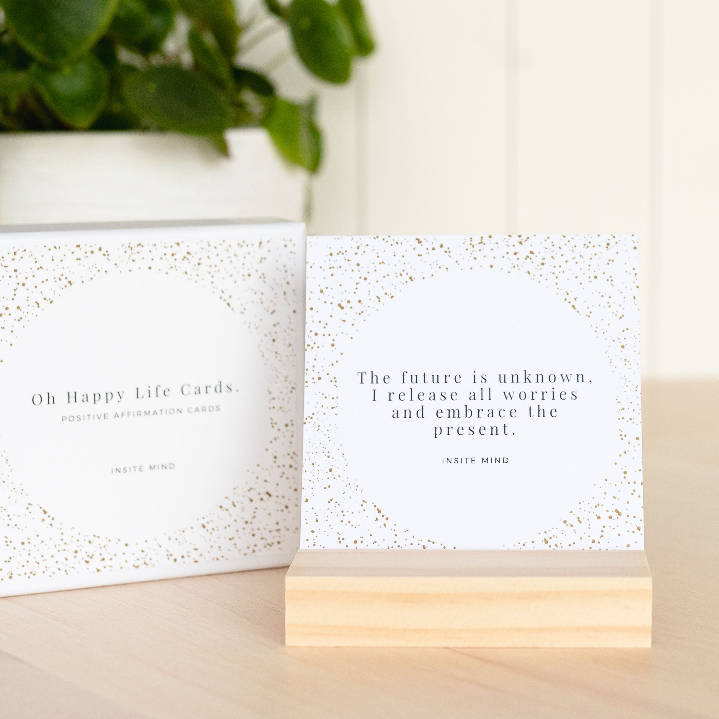 A beautifully designed set of Oh Happy Life affirmation cards displayed with a stylish card stand, featuring positive messages for daily inspiration.