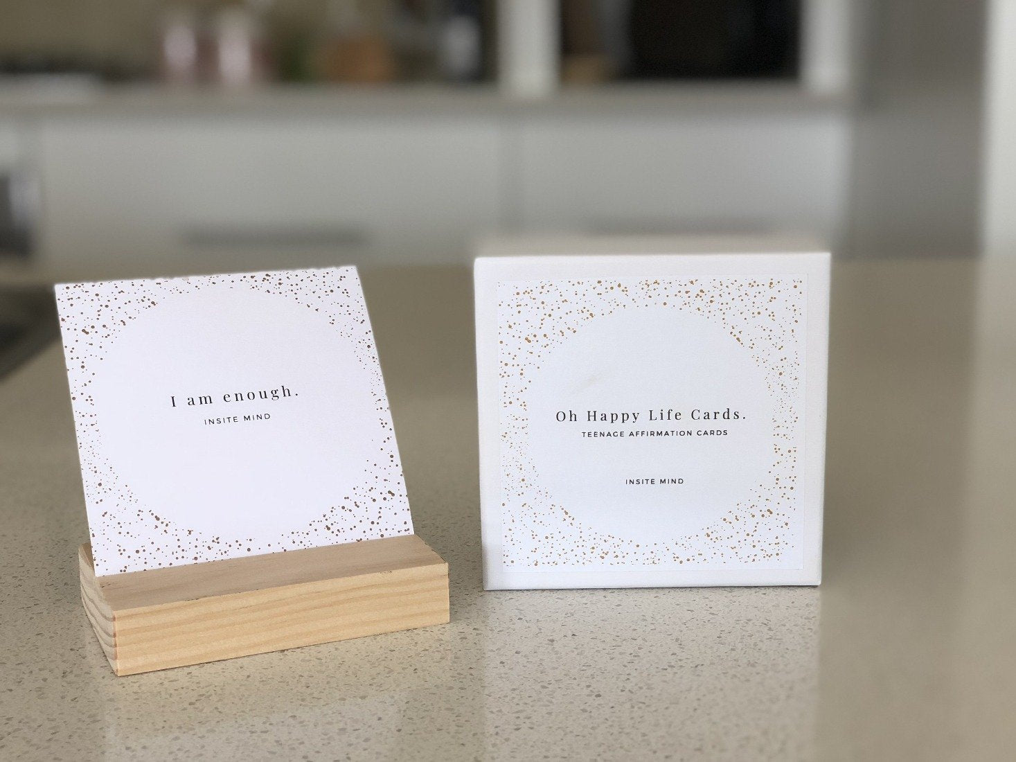 A beautifully designed set of Oh Happy Life affirmation cards displayed with a stylish card stand, featuring positive messages for daily inspiration.