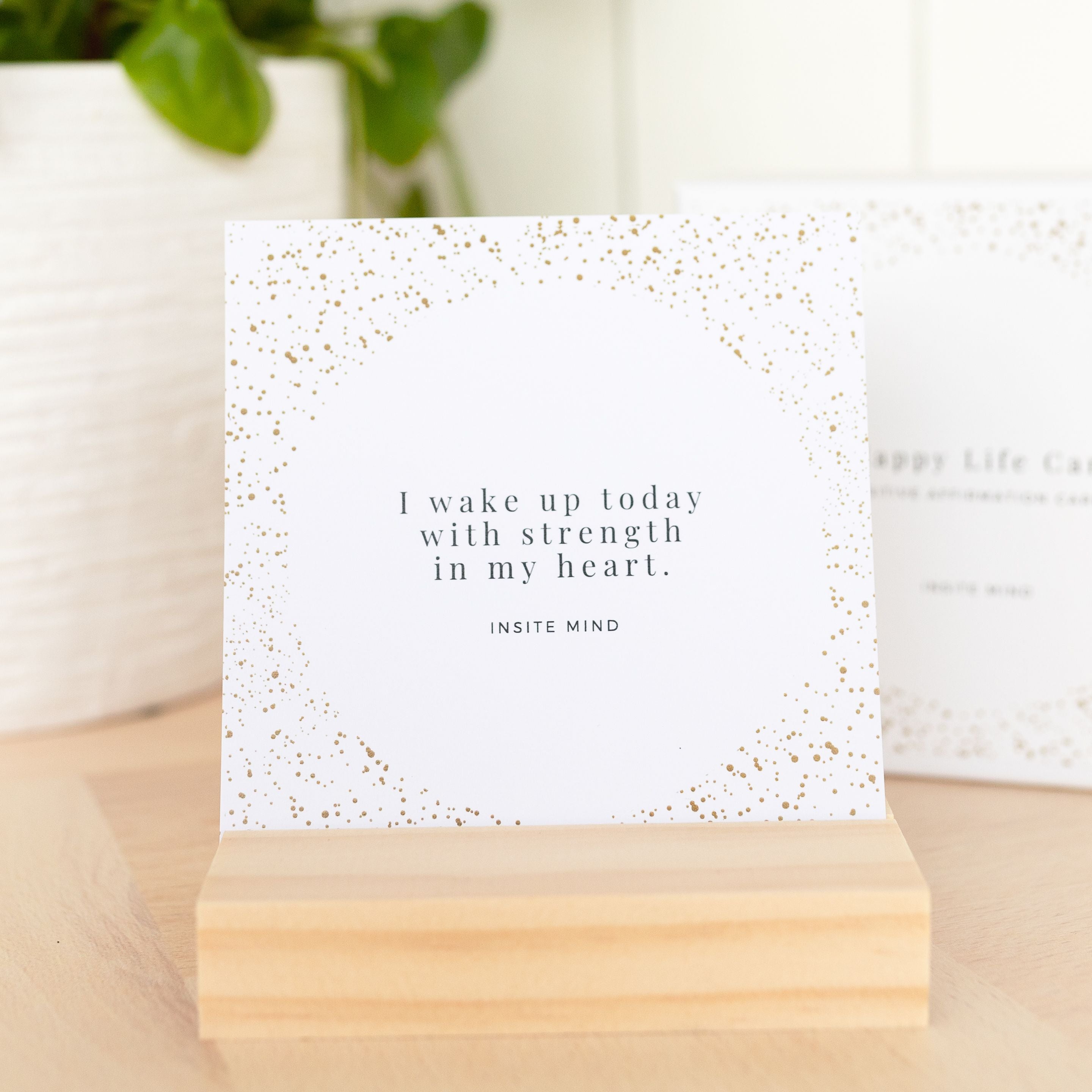 A beautifully designed set of Oh Happy Life affirmation cards displayed with a stylish card stand, featuring positive messages for daily inspiration.