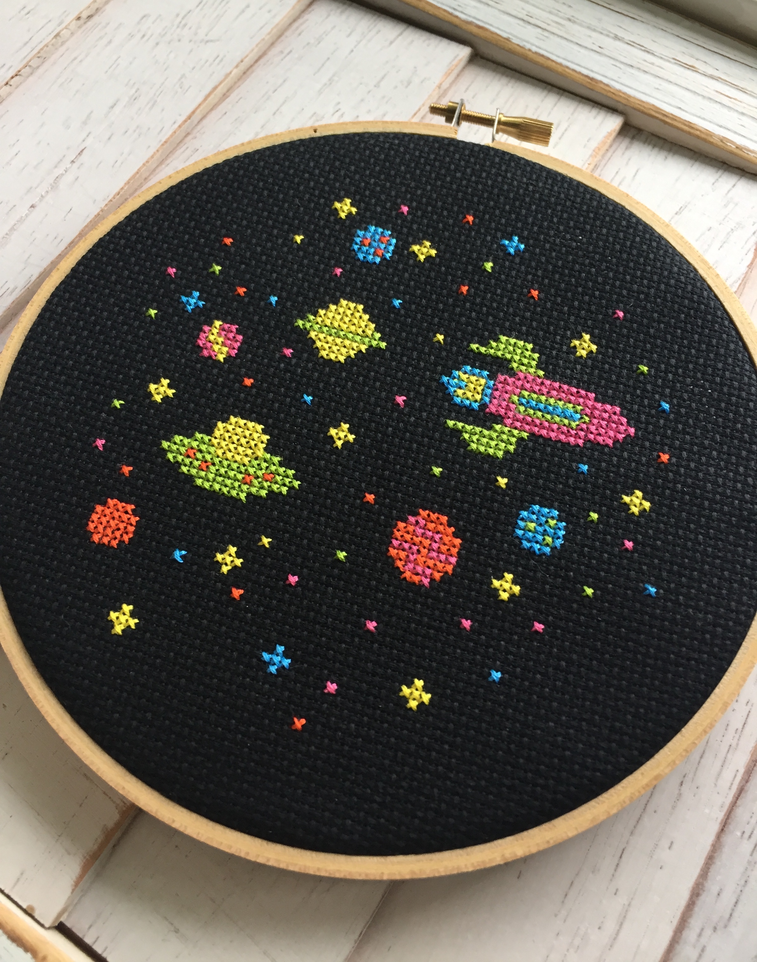 Colorful counted cross stitch kit featuring a rocket ship, planets, and stars, perfect for beginners.