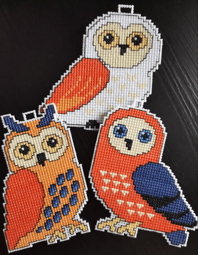 A counted cross-stitch kit featuring owls, including plastic canvas, colorful threads, and instructions.