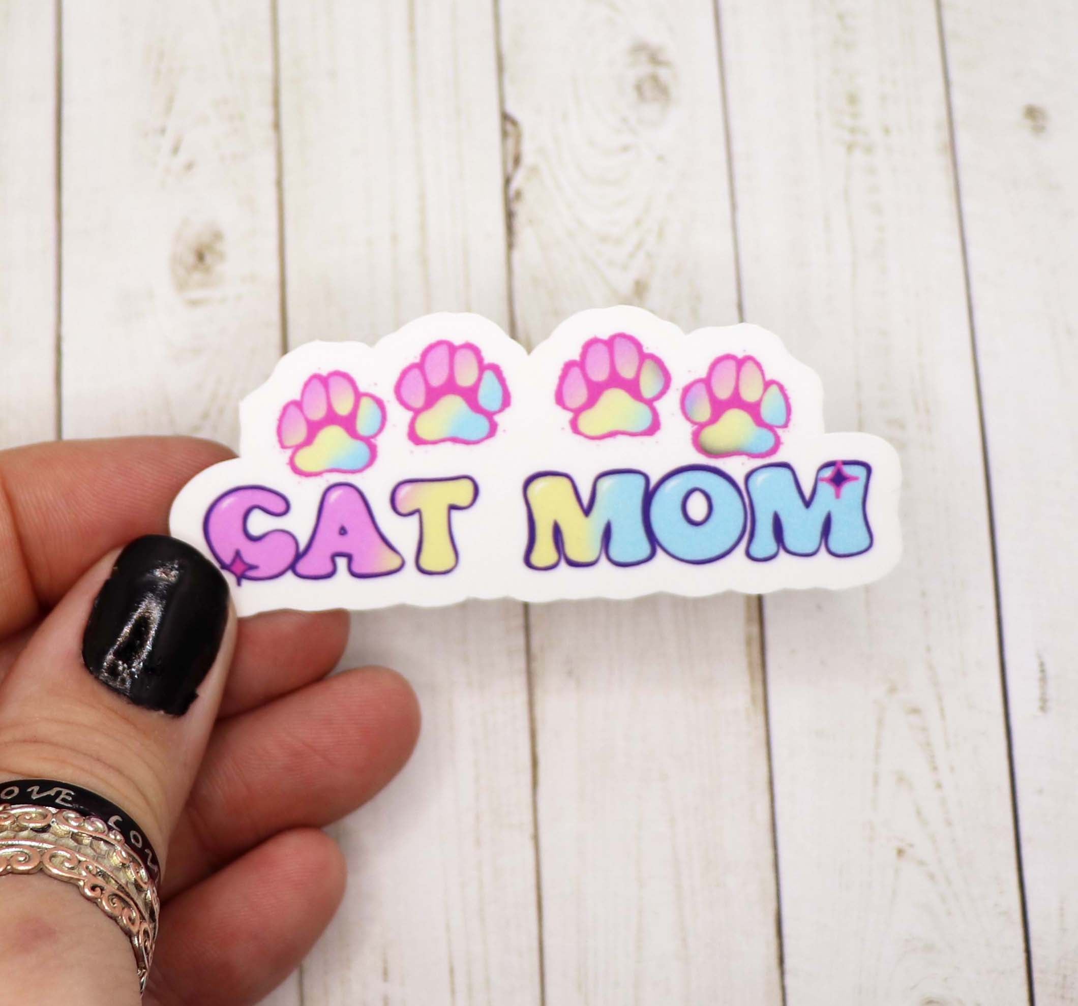 A pastel-colored sticker featuring a cute cat design with the text 'Cat Mom', perfect for personalizing items.