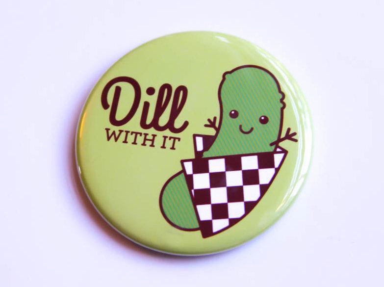 A cheerful 'Dill With It!' pickle magnet and pin featuring a happy pickle character and vibrant colors.