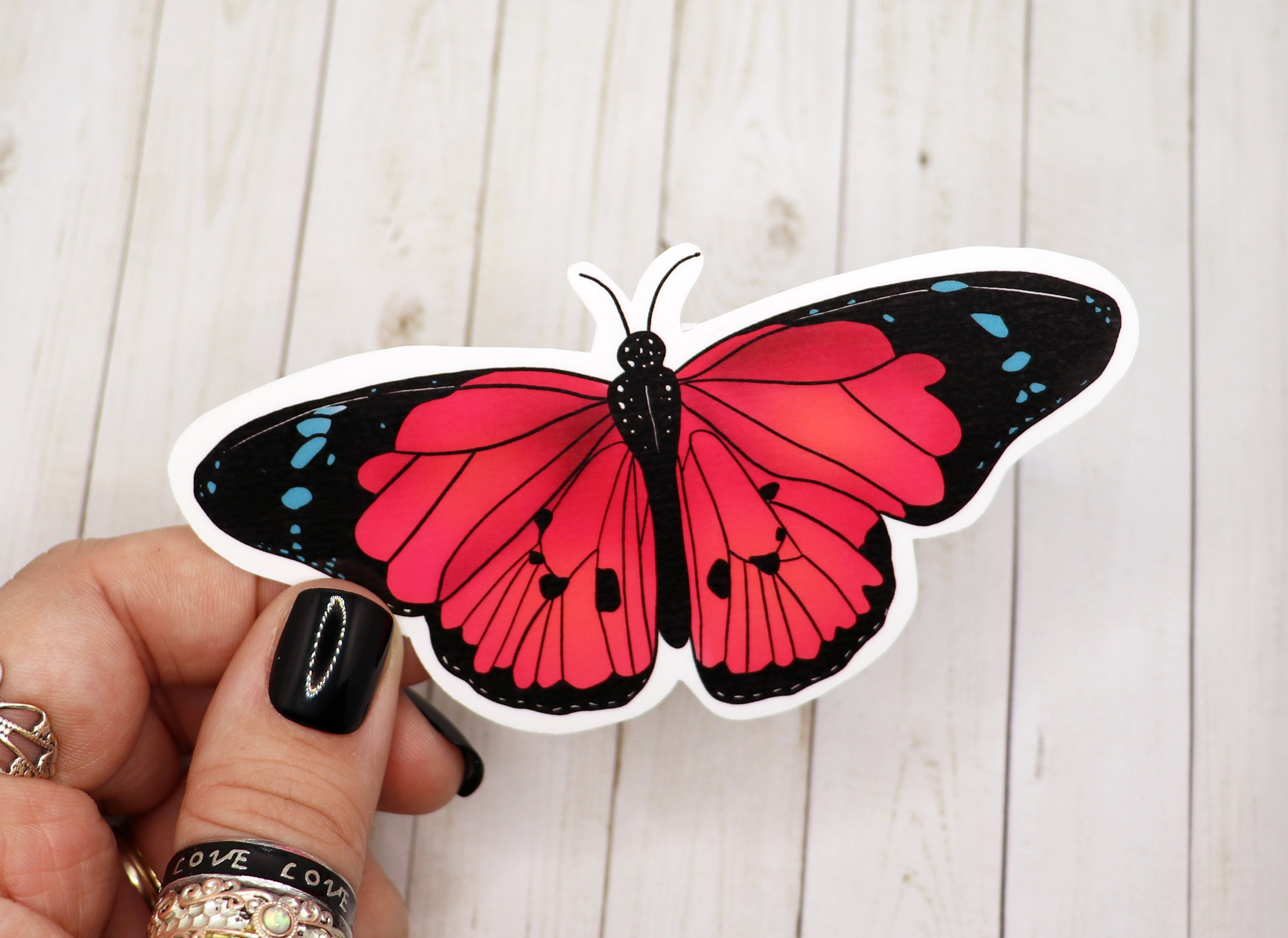 A vibrant pink butterfly sticker on a white background, showcasing its intricate design and matte finish.