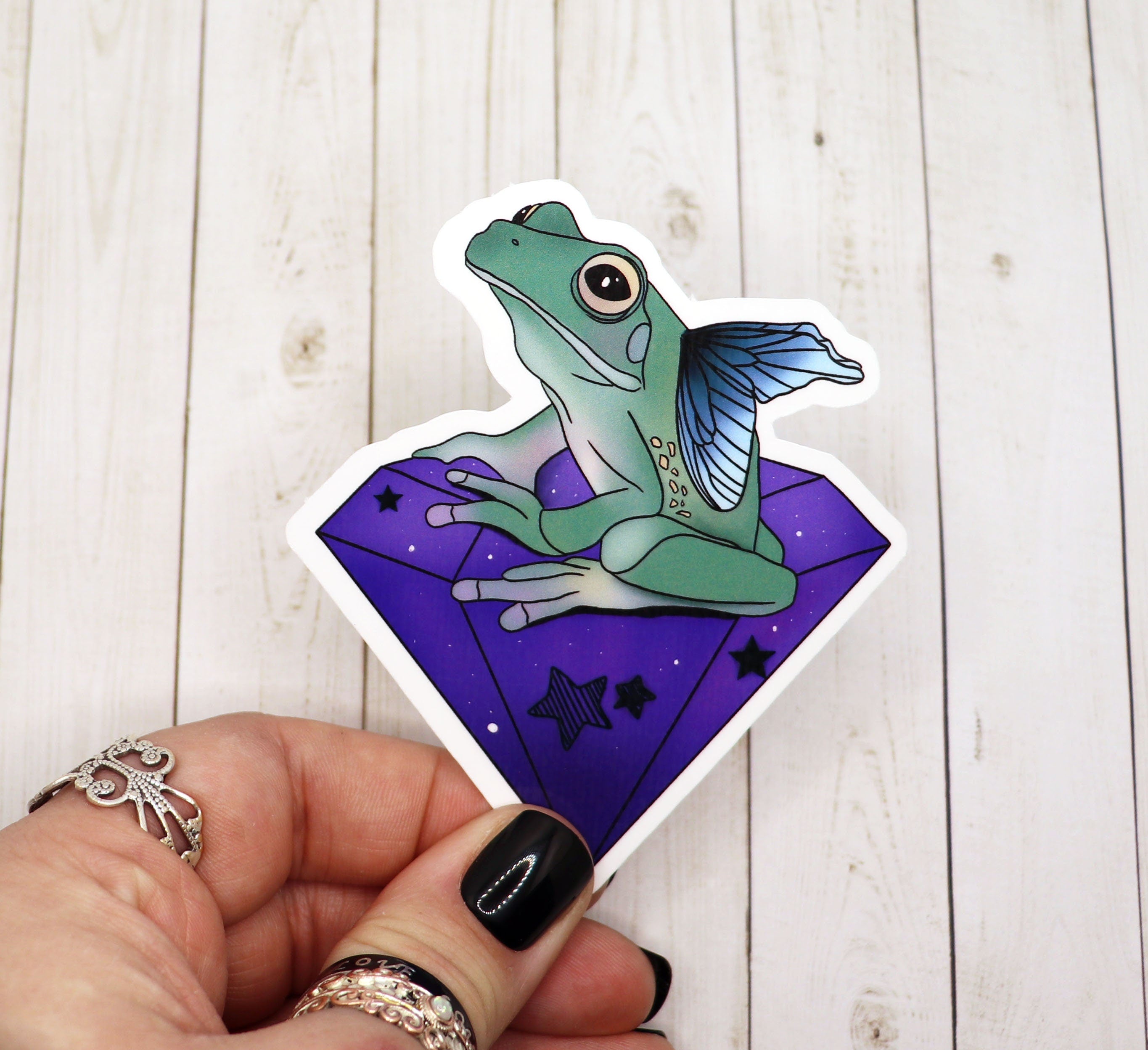 A vibrant purple crystal frog fairy sticker on a matte vinyl surface, showcasing intricate details and colors.