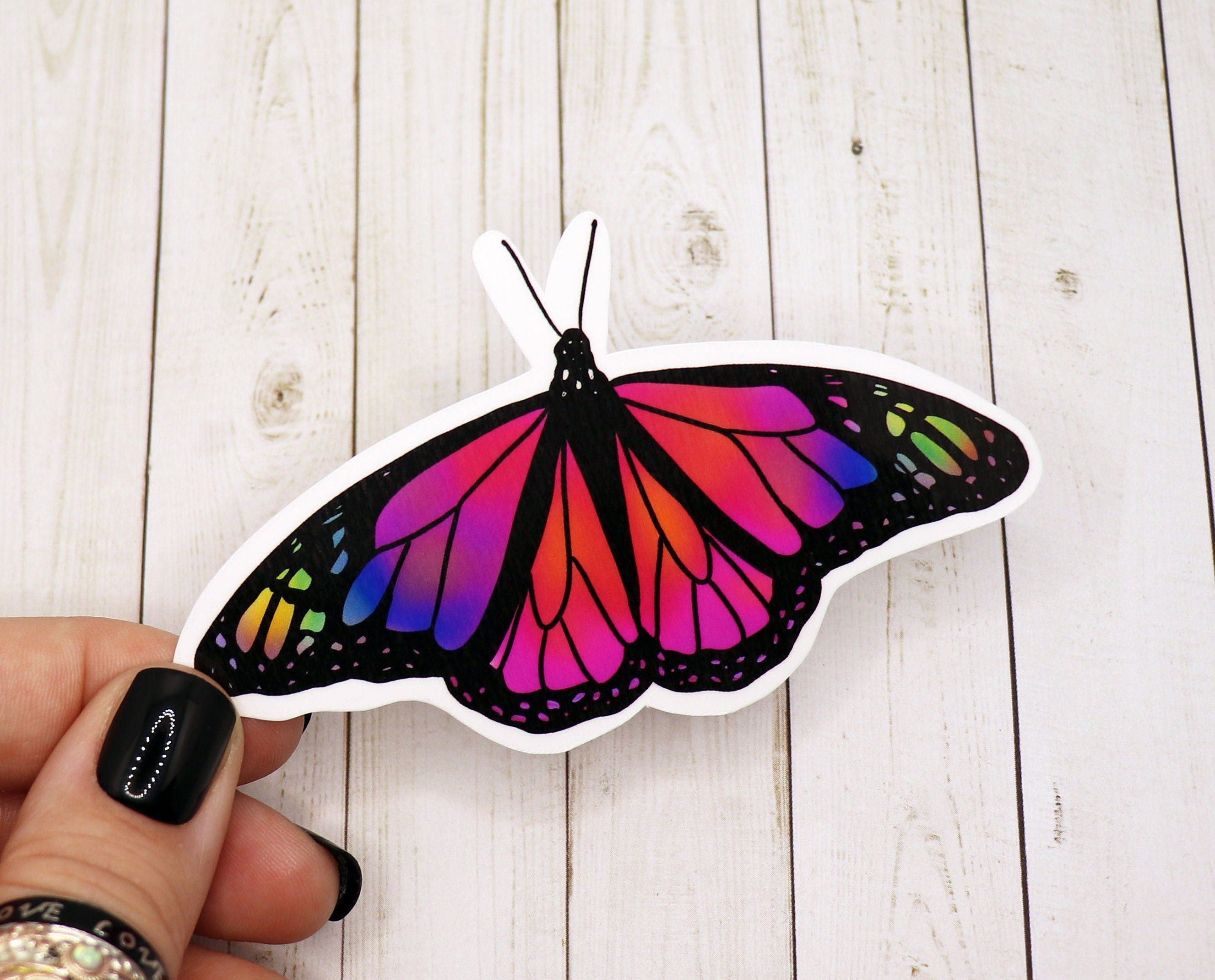 A colorful rainbow butterfly sticker on a white background, showcasing vibrant hues and intricate details.