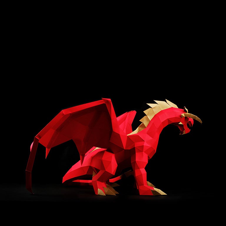 A stunning red and gold paper dragon model in a predatory stance with wings spread, showcasing intricate details and craftsmanship.