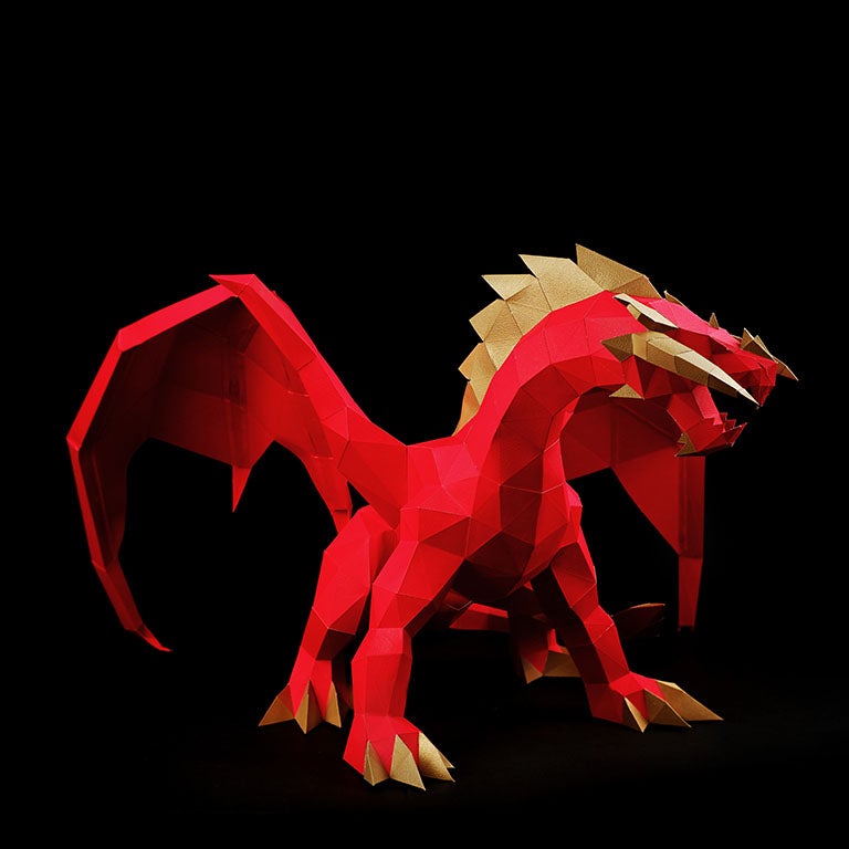 A stunning red and gold paper dragon model in a predatory stance with wings spread, showcasing intricate details and craftsmanship.