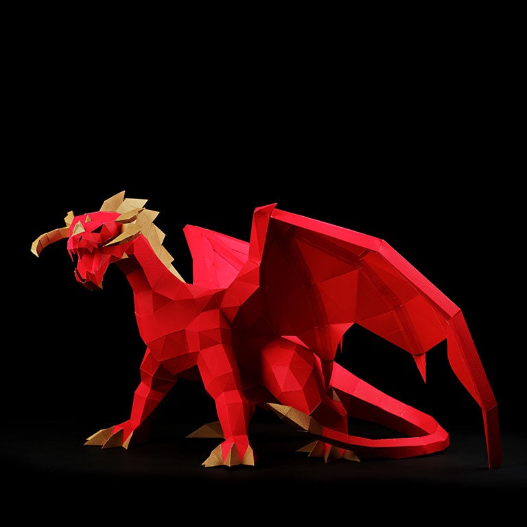 A stunning red and gold paper dragon model in a predatory stance with wings spread, showcasing intricate details and craftsmanship.