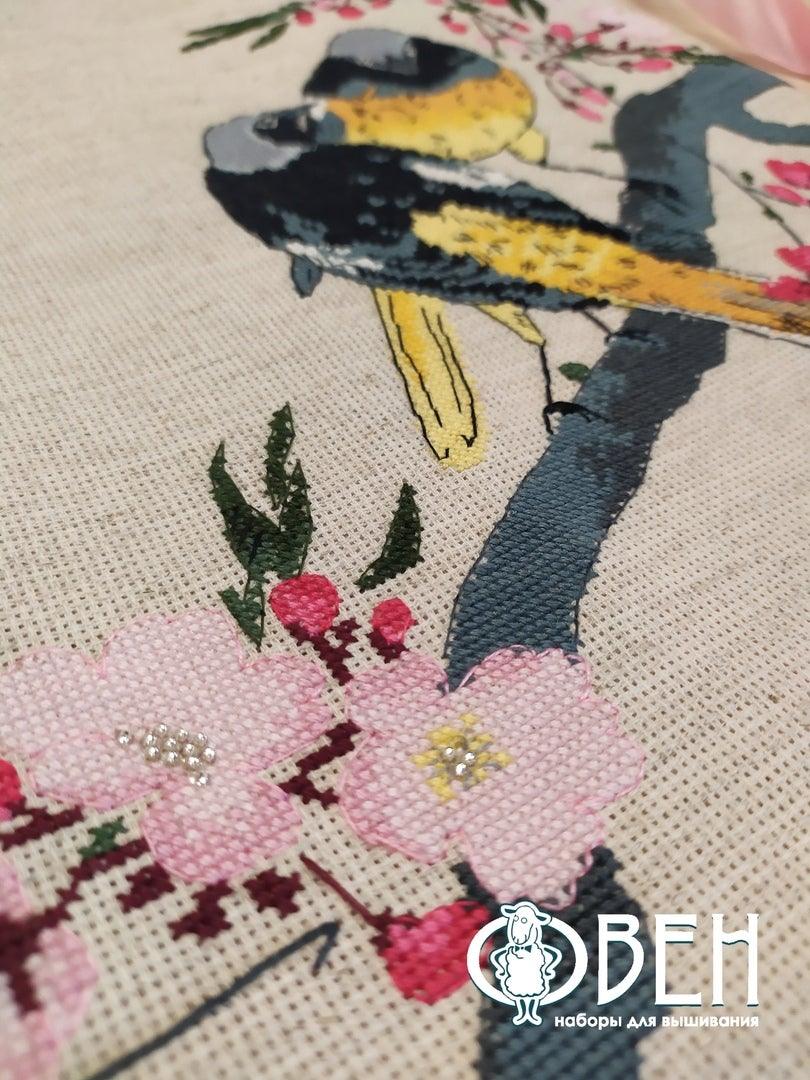 A counted cross stitch kit featuring redstarts on a cherry branch, including linen canvas, threads, and needle.