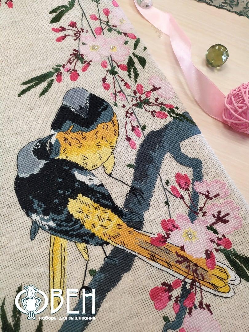 A counted cross stitch kit featuring redstarts on a cherry branch, including linen canvas, threads, and needle.