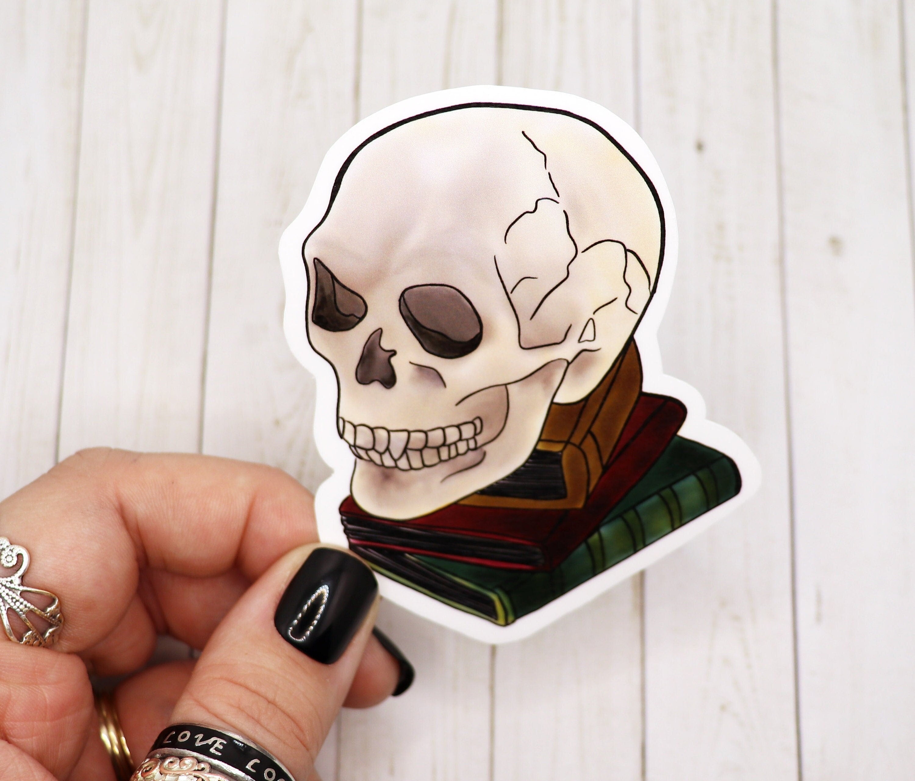 A stylish Skull on Books sticker featuring a skull resting on a stack of books, printed on high-quality matte vinyl.