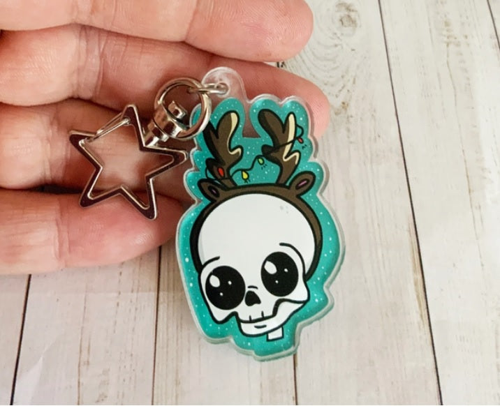 A festive Skull Reindeer Acrylic Keychain featuring a unique illustration, attached to a gold star keyring.