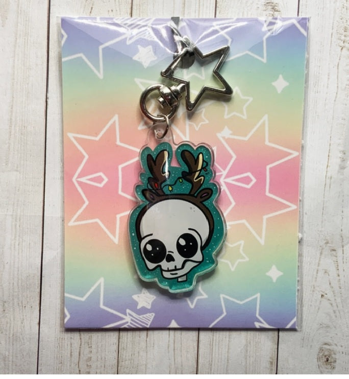 A festive Skull Reindeer Acrylic Keychain featuring a unique illustration, attached to a gold star keyring.