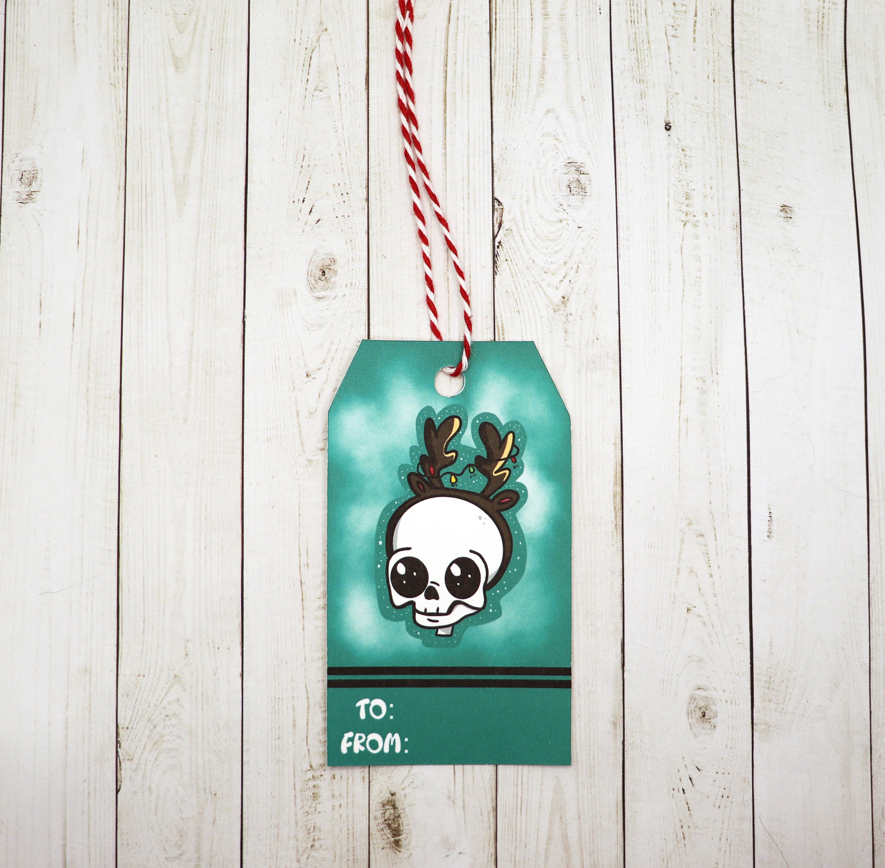 A set of Skull Reindeer Gift Tags featuring a whimsical design, printed on heavy white cardstock, with red and white twine included.