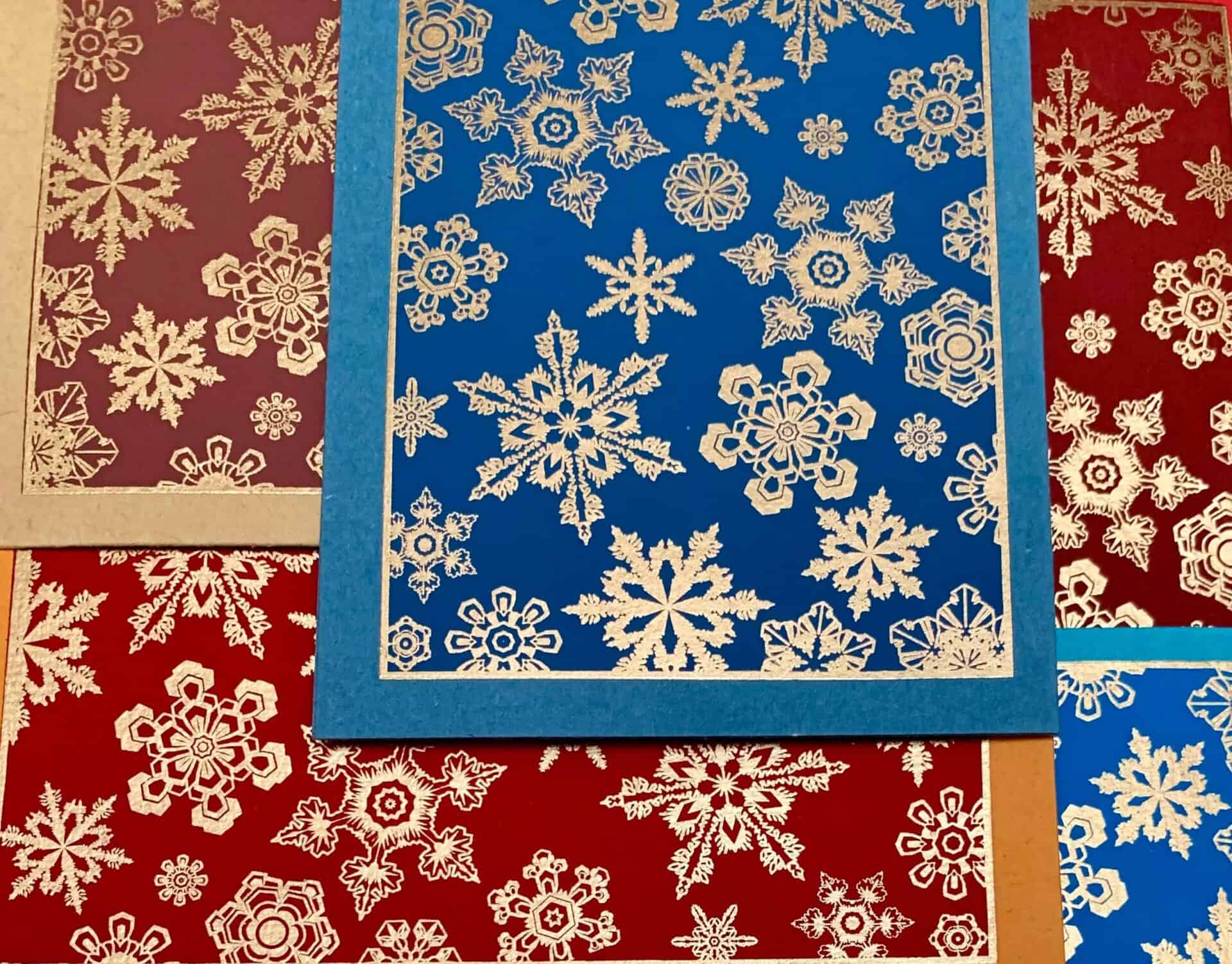 A collection of handmade SNOWFLAKE greeting cards featuring unique textures and vintage designs, accompanied by vanilla envelopes.