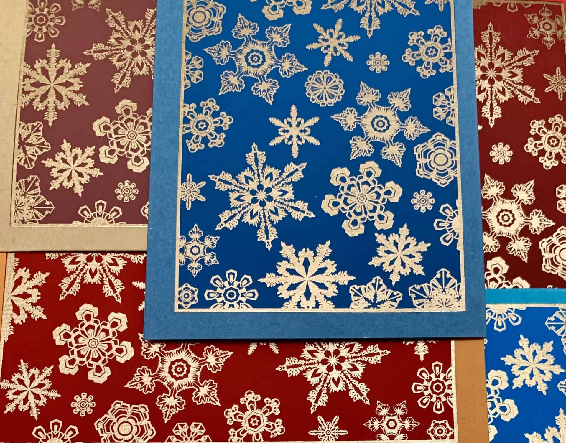 A collection of handmade SNOWFLAKE greeting cards featuring unique textures and vintage designs, accompanied by vanilla envelopes.