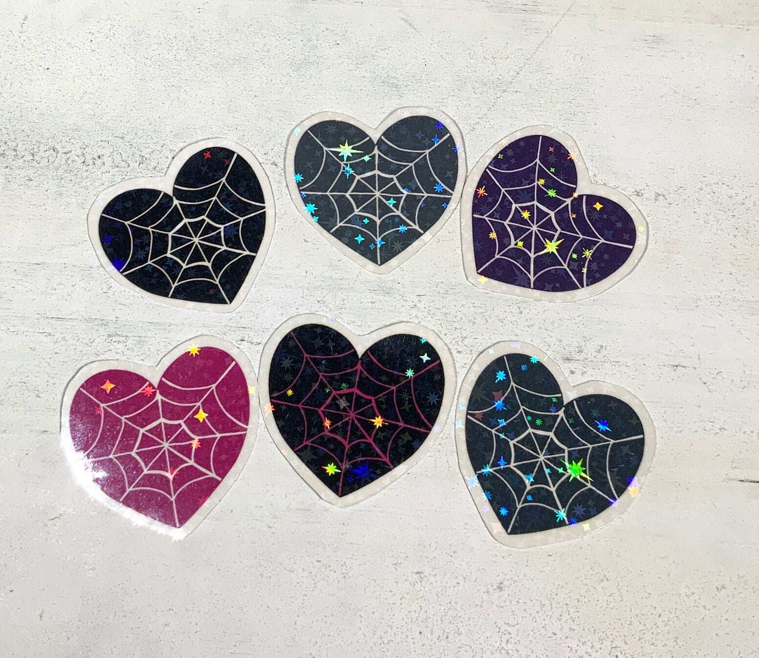 A pack of six spider web heart stickers in various designs, printed on high-quality matte vinyl with a laminated finish for durability.