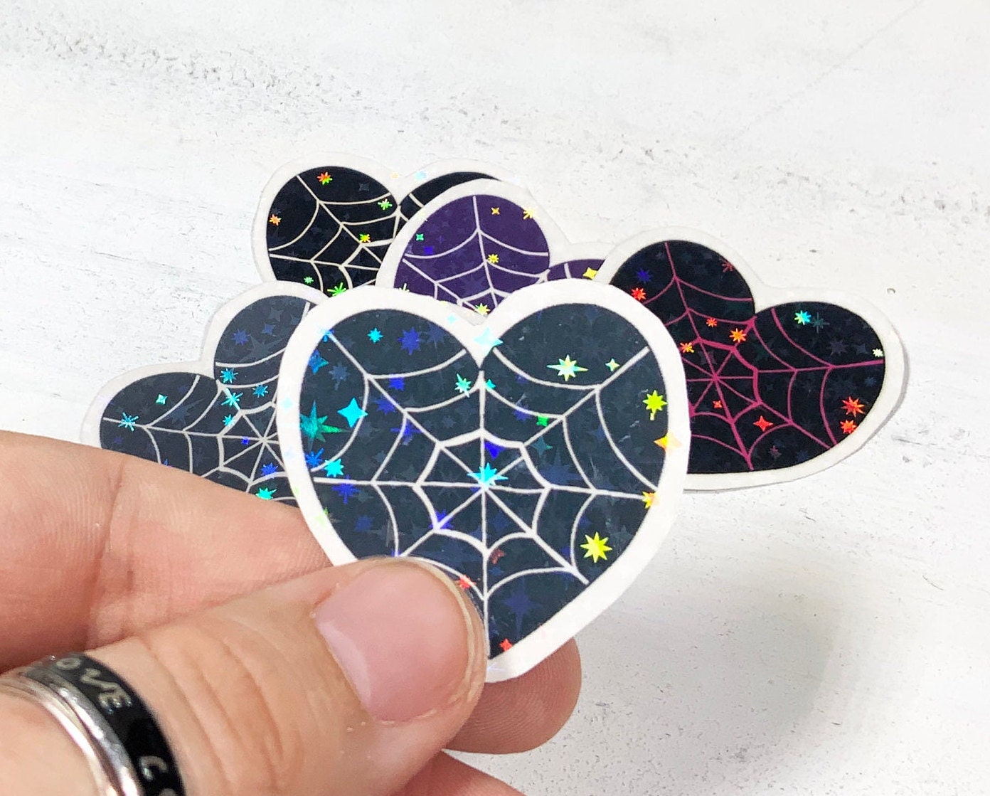 A pack of six spider web heart stickers in various designs, printed on high-quality matte vinyl with a laminated finish for durability.