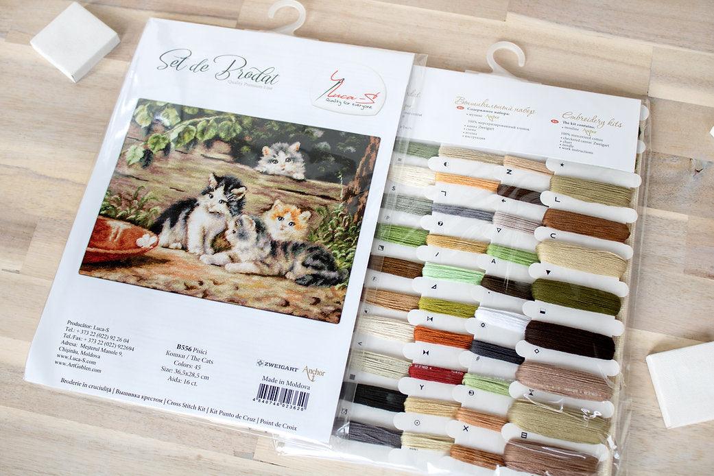 The Cats B556L Counted Cross-Stitch Kit featuring Aida canvas, colorful threads, and a needle for crafting.