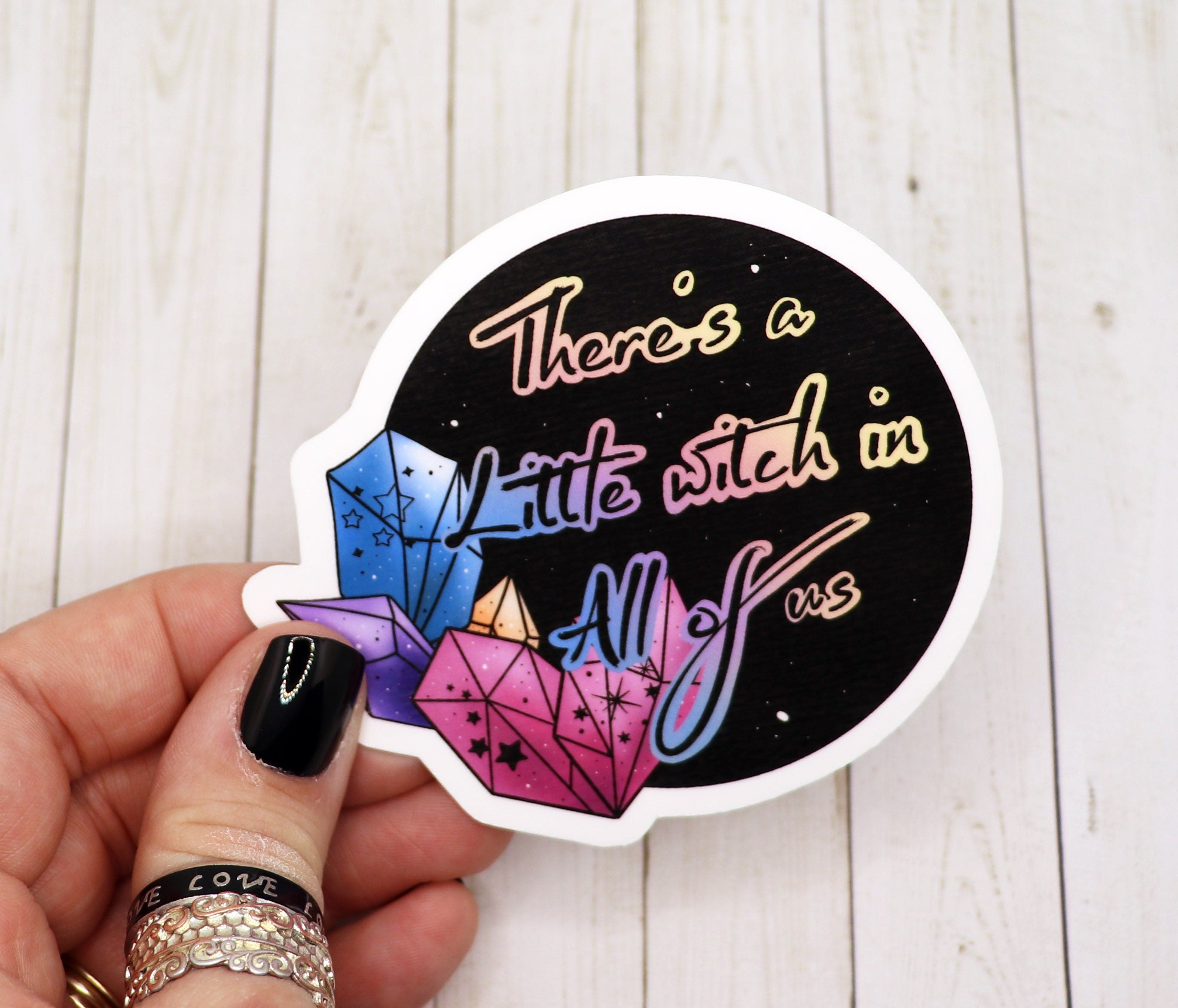 A whimsical vinyl sticker featuring the phrase 'There's a Little Witch in All of Us' with a magical design, perfect for personalizing items.