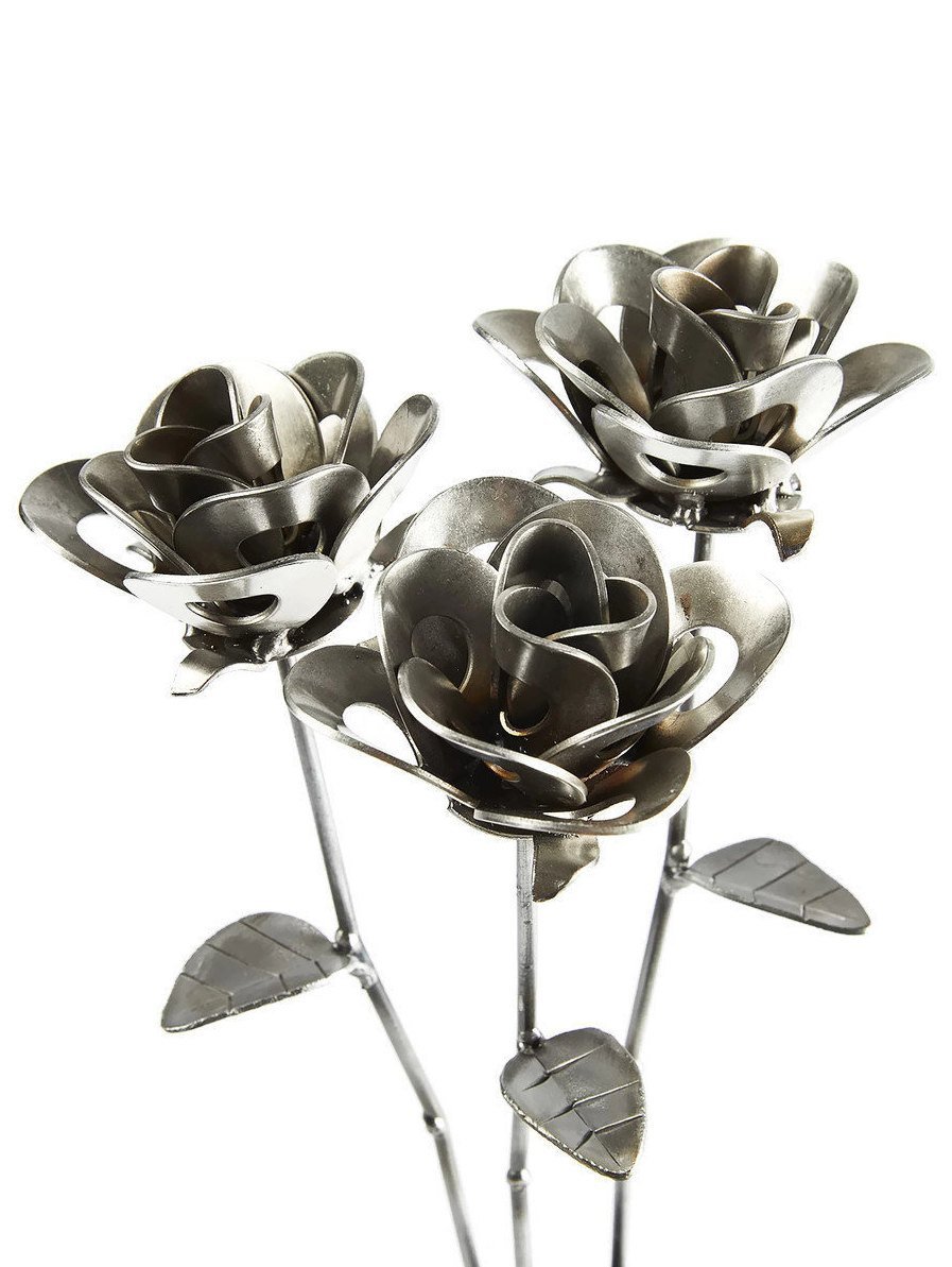 Three handcrafted welded steel roses made from recycled materials, showcasing unique designs and a rustic finish.