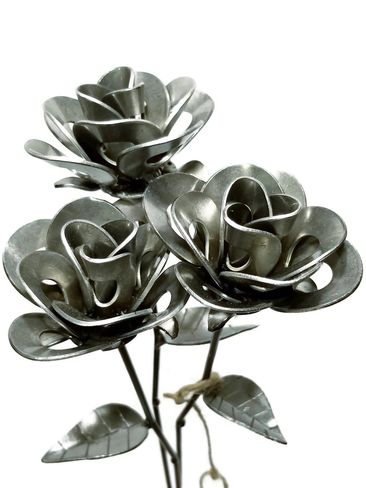 Three handcrafted welded steel roses made from recycled materials, showcasing unique designs and a rustic finish.