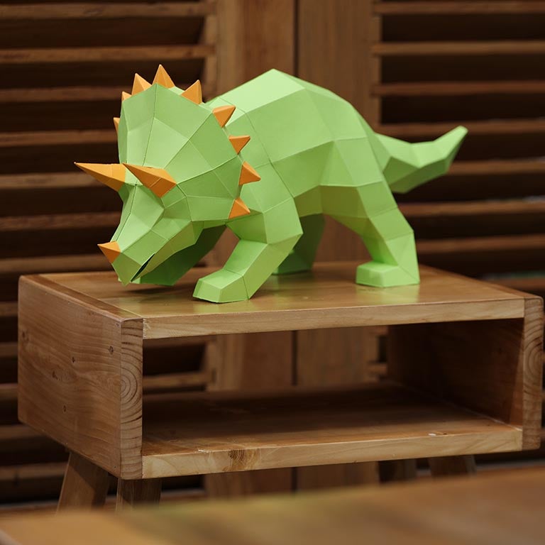 A vibrant green Triceratops 3D paper model lamp with orange horn spikes, showcasing intricate details and a unique design.