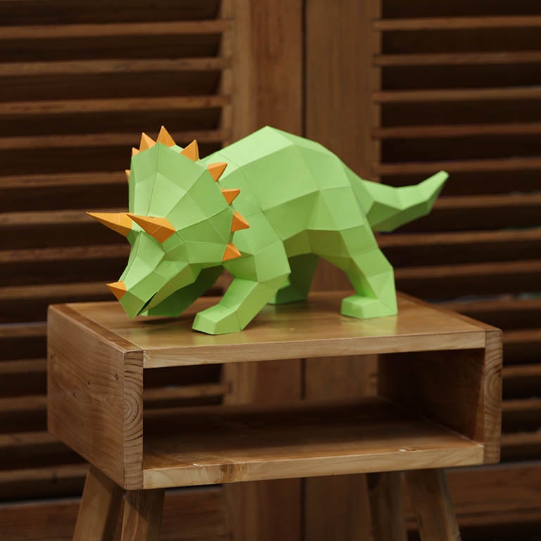 A vibrant green Triceratops 3D paper model lamp with orange horn spikes, showcasing intricate details and a unique design.