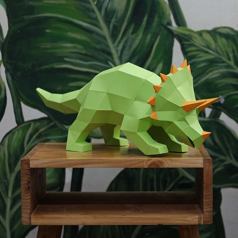 A vibrant green Triceratops 3D paper model lamp with orange horn spikes, showcasing intricate details and a unique design.