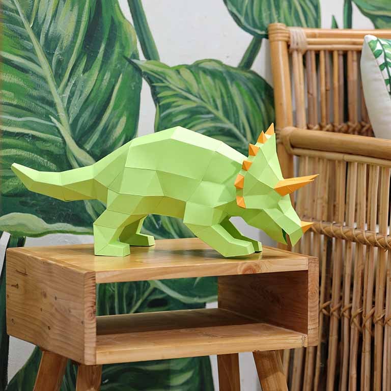 A vibrant green Triceratops 3D paper model lamp with orange horn spikes, showcasing intricate details and a unique design.