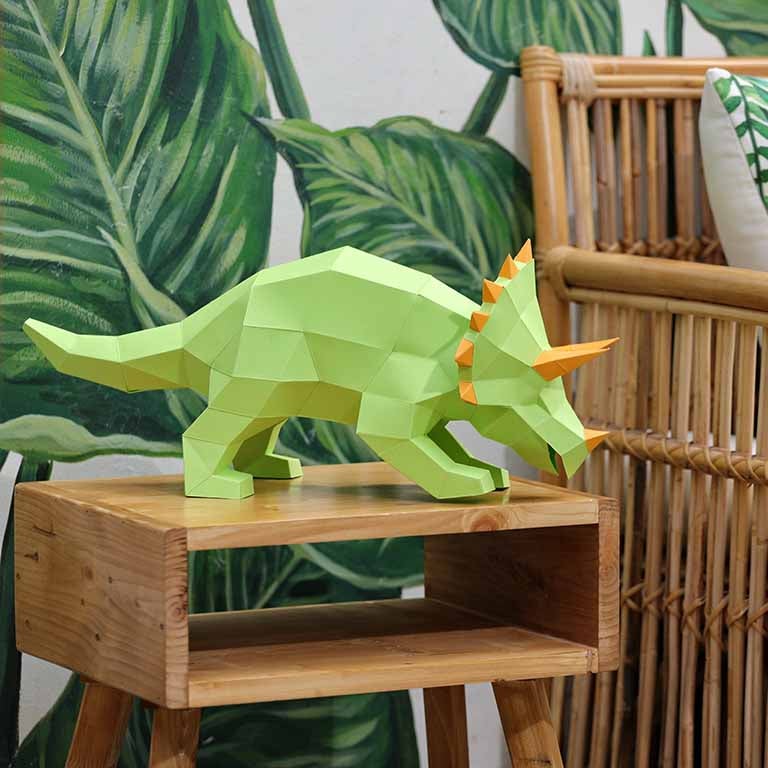 A vibrant green Triceratops 3D paper model lamp with orange horn spikes, showcasing intricate details and a unique design.