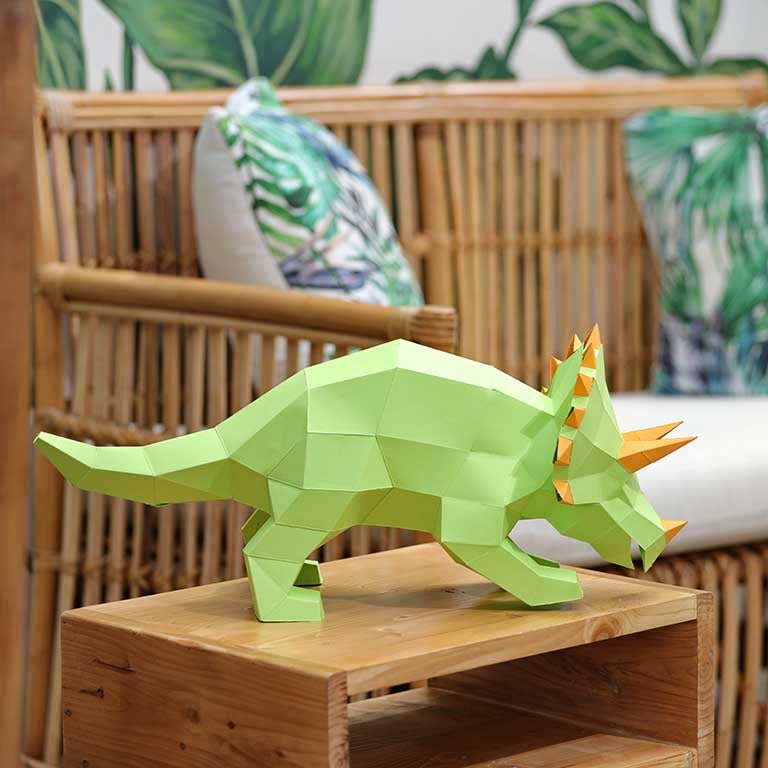 A vibrant green Triceratops 3D paper model lamp with orange horn spikes, showcasing intricate details and a unique design.