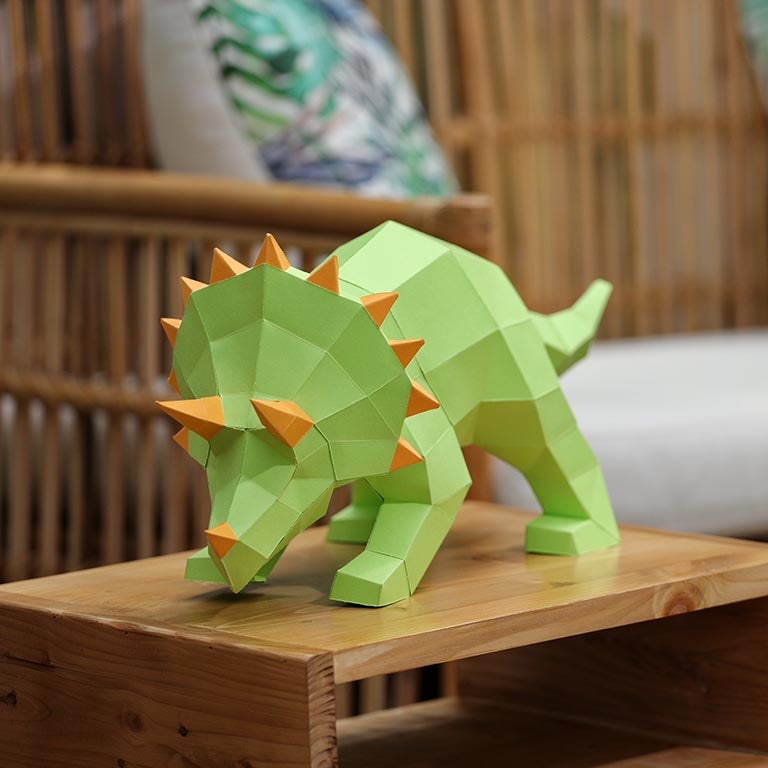 A vibrant green Triceratops 3D paper model lamp with orange horn spikes, showcasing intricate details and a unique design.