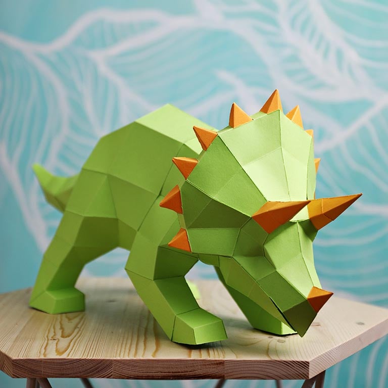 A vibrant green Triceratops 3D paper model lamp with orange horn spikes, showcasing intricate details and a unique design.