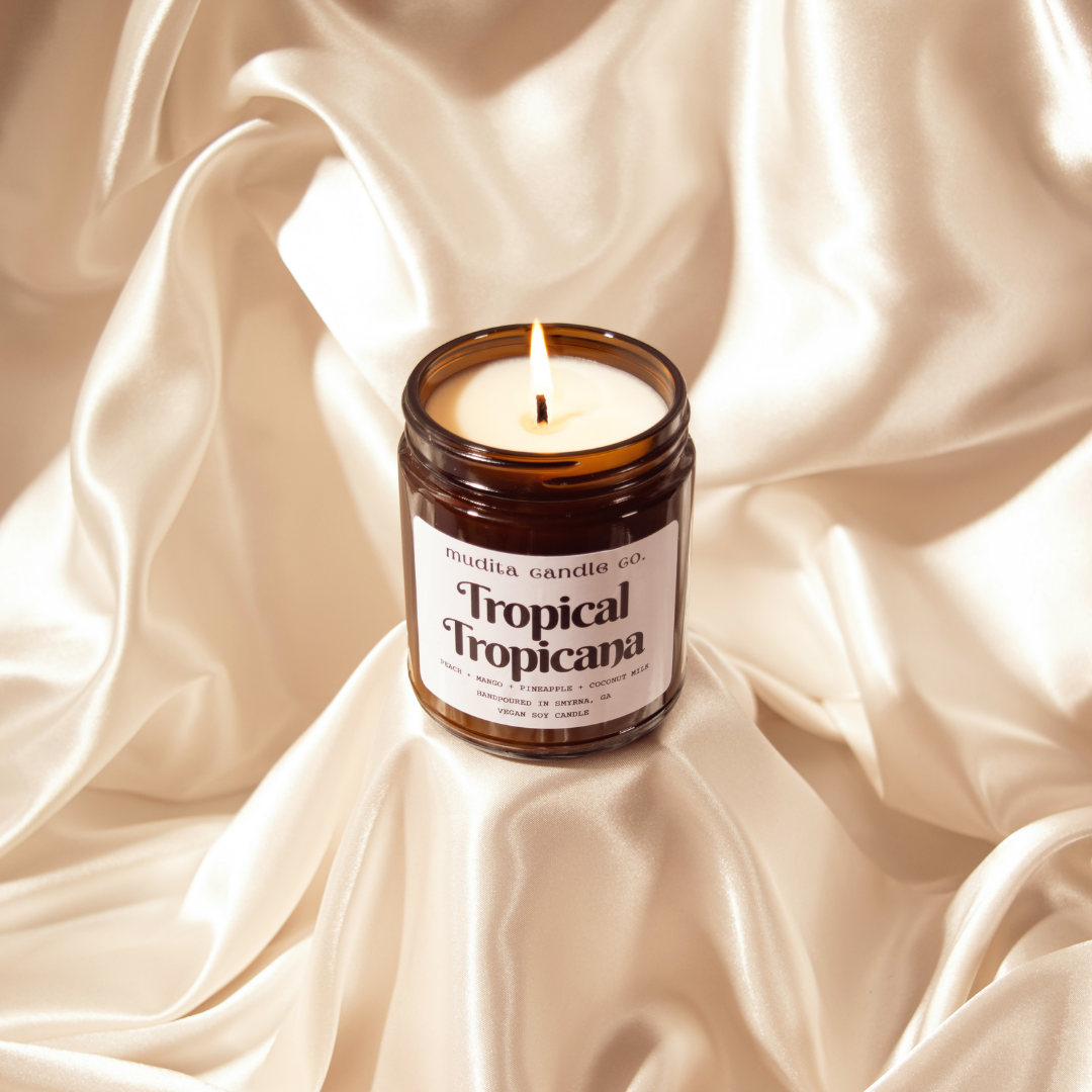 Tropical Tropicana candle in amber glass jar with gold lid, showcasing tropical fruit scents.