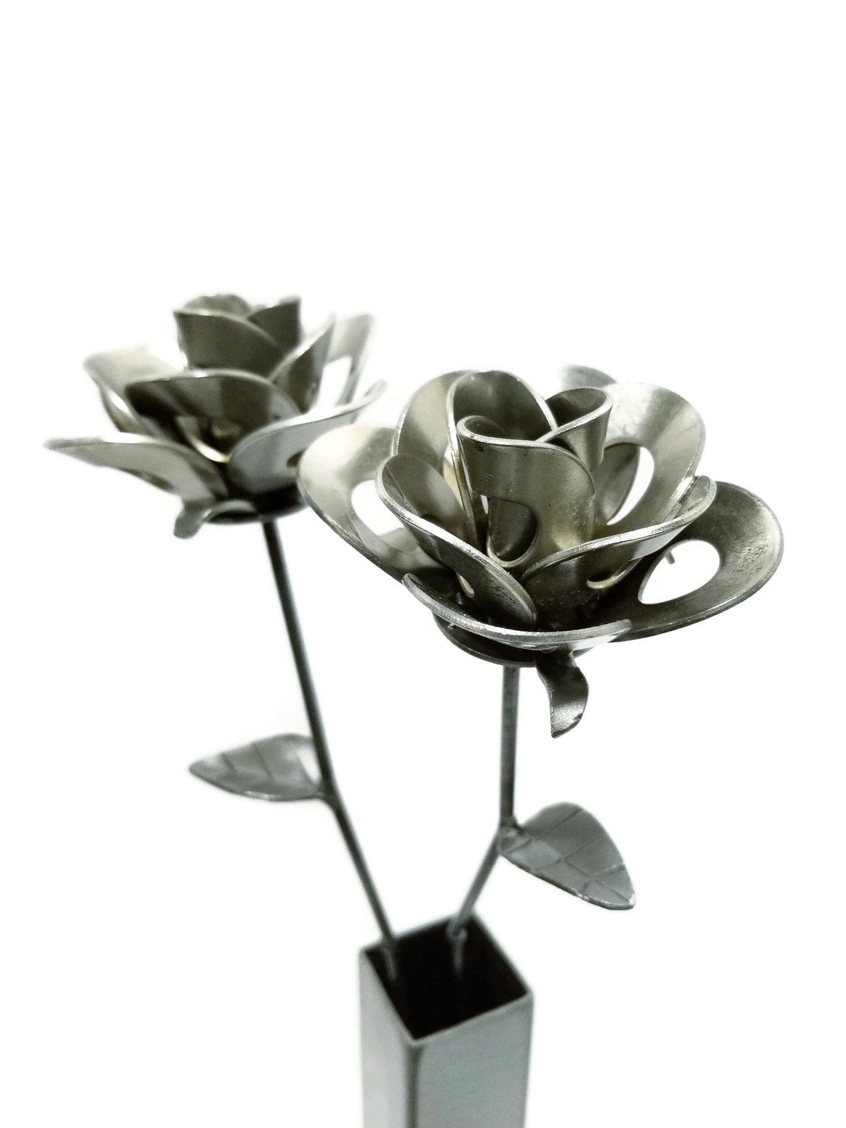 Two handcrafted metal roses in a rustic vase, showcasing a unique steampunk design made from recycled materials.