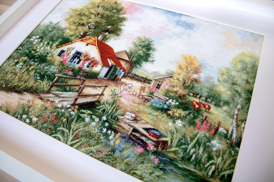 Village landscape counted cross-stitch kit featuring a house, creek, geese, and cows with vibrant colors and detailed design.