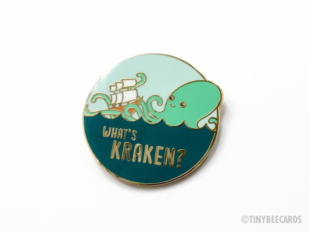 What's Kraken Hard Enamel Pin featuring a cute kraken and ship design on a gold metal background.