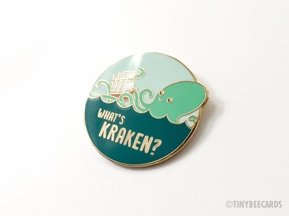 What's Kraken Hard Enamel Pin featuring a cute kraken and ship design on a gold metal background.