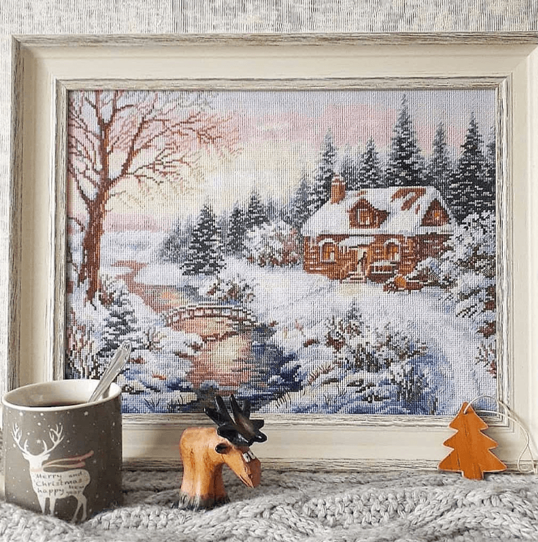 Counted cross-stitch kit featuring a winter scene with white aida fabric and colorful threads.