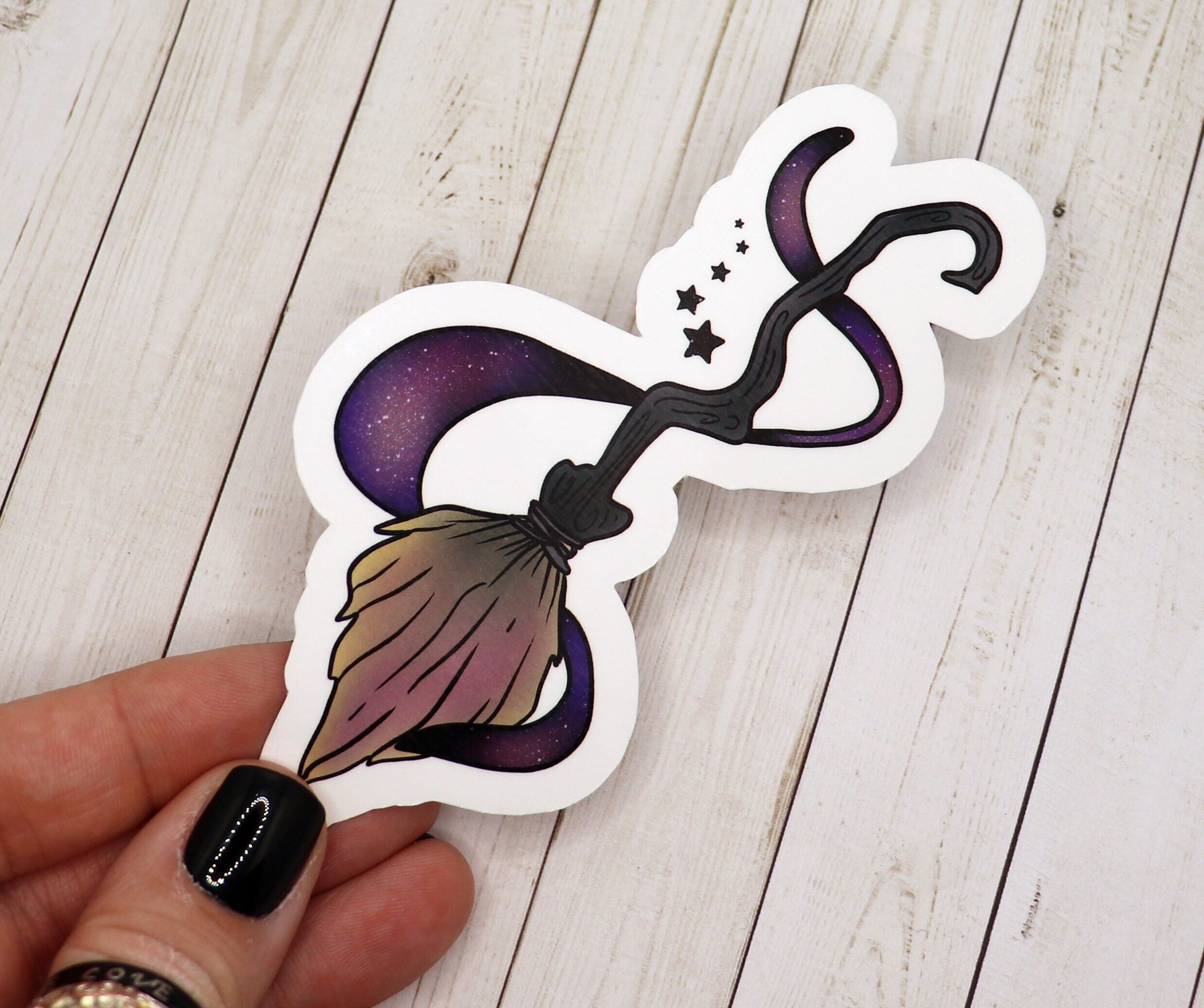 A vibrant Witch Broom Sticker on a matte vinyl surface, showcasing intricate details and a whimsical design.