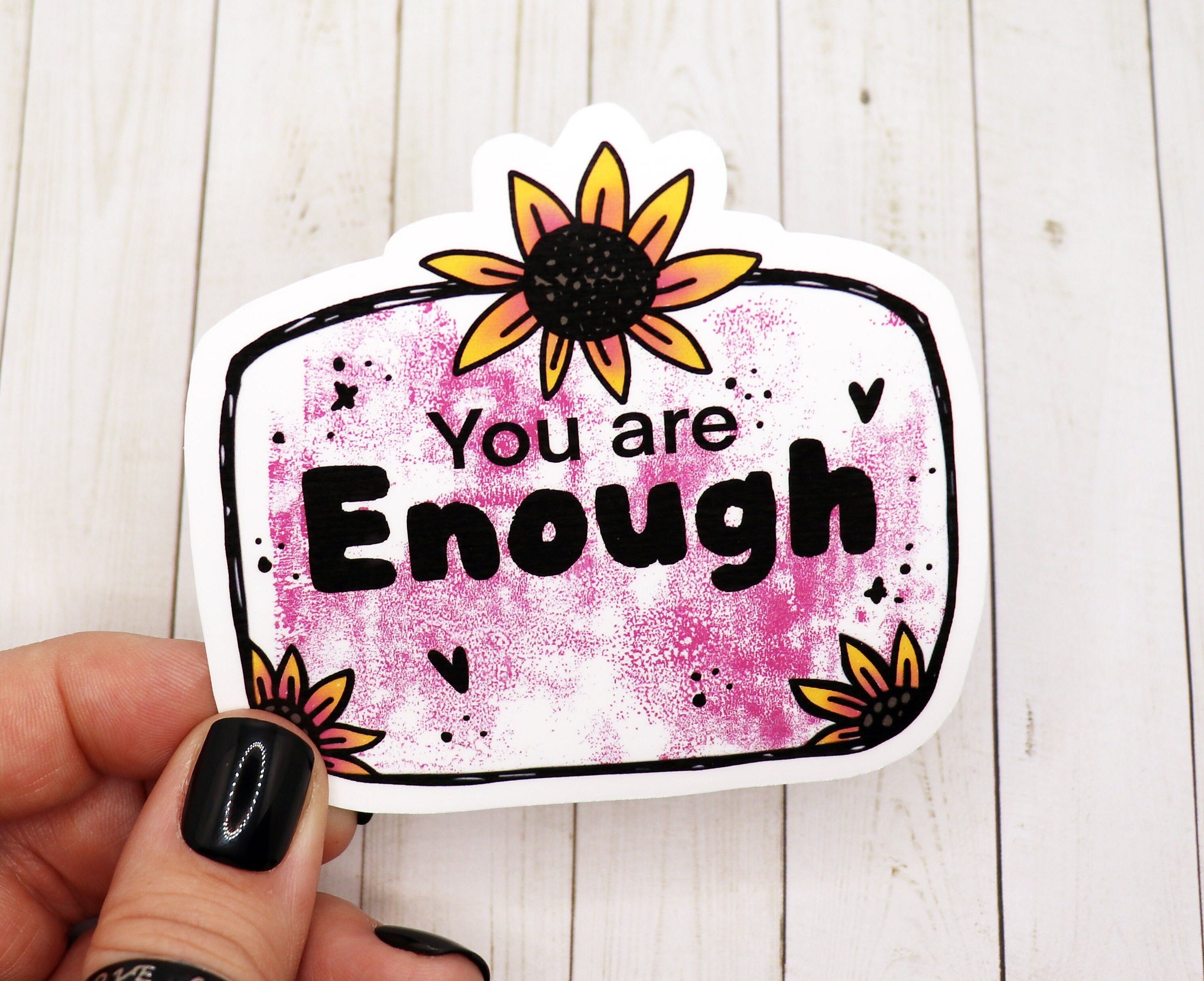 A vibrant 'You are Enough' vinyl sticker on a smooth surface, showcasing its matte finish and empowering message.